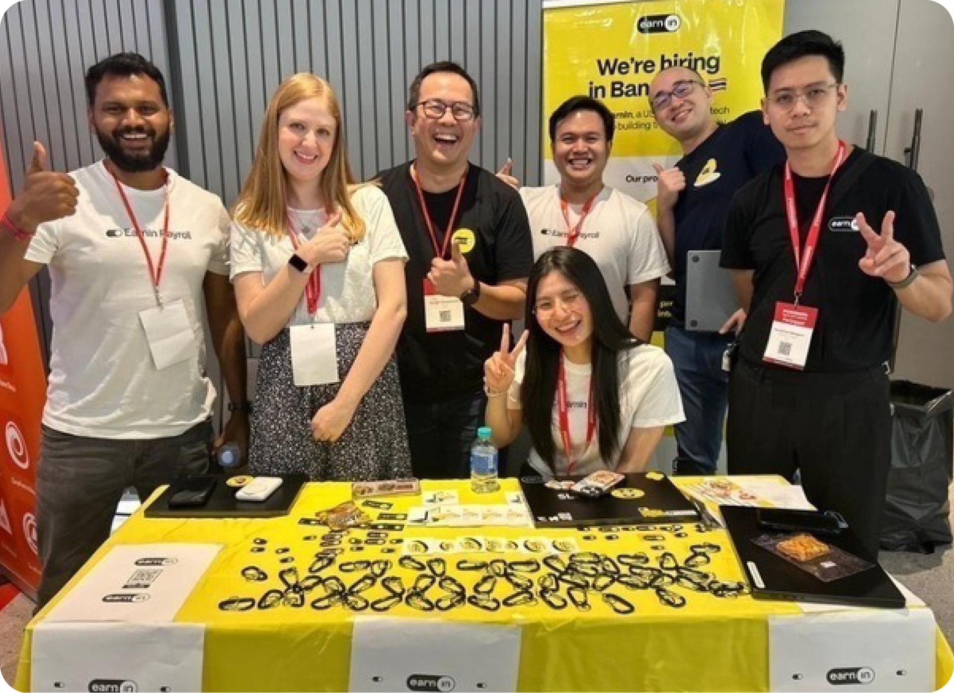 EarnIn teammates at a hiring booth giving a thumbs up
