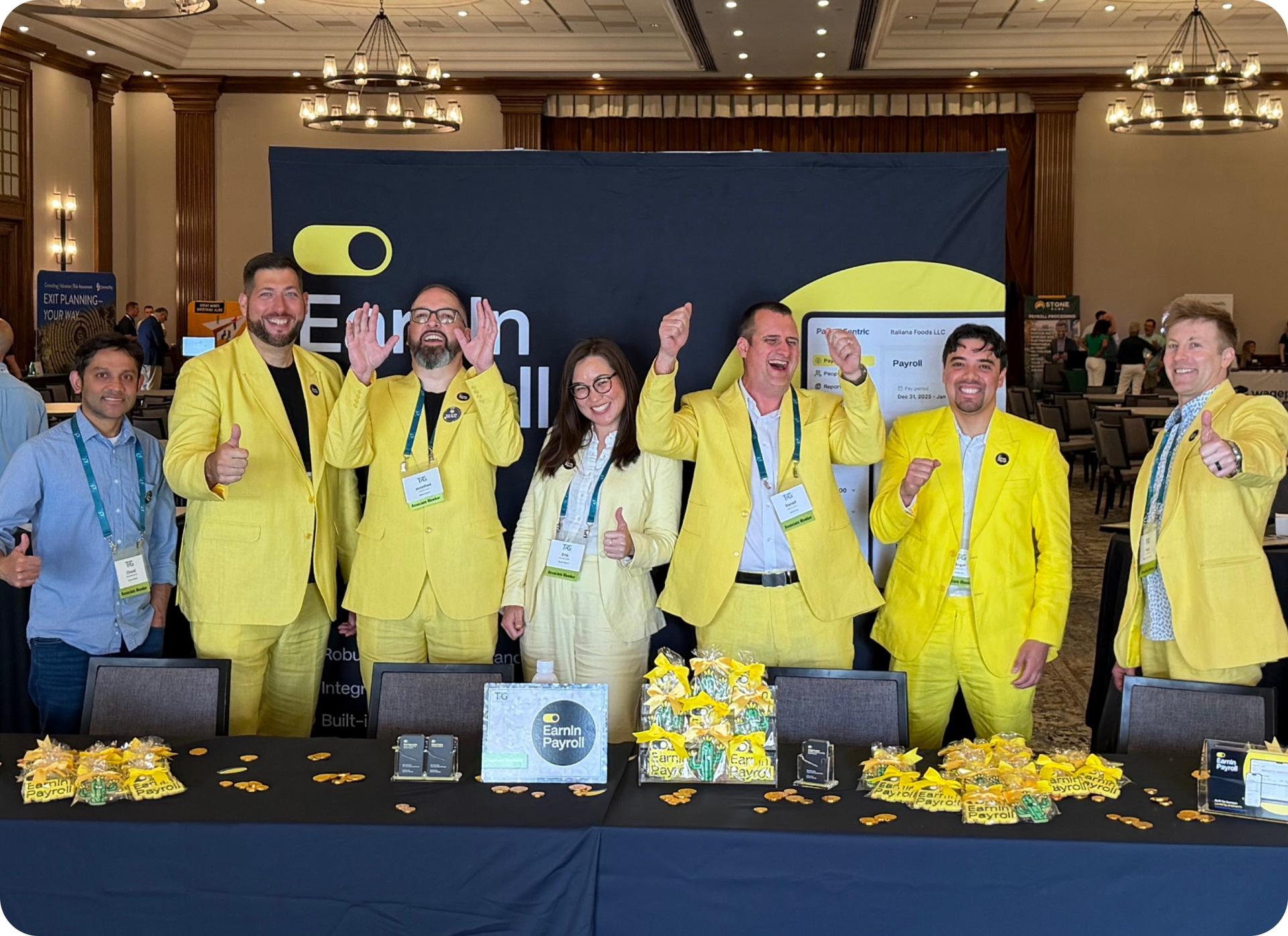 EarnIn teammates in yellow suits celebrating at a conference booth